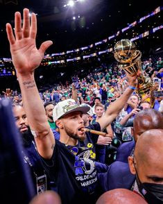 a man holding up a trophy in front of a crowd at a basketball game with other people