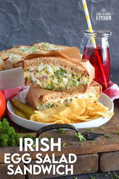 a sandwich cut in half sitting on top of a plate next to chips and tomatoes