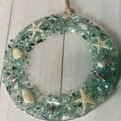 a glass wreath with shells and seashells hanging on a wooden wall ornament