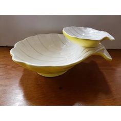 two yellow and white bowls sitting on top of a wooden table next to a wall