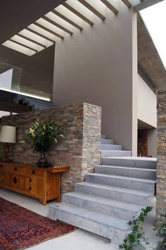 a living room filled with furniture next to a stone wall and stair leading up to the second floor