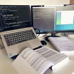 an open book sitting on top of a desk next to a laptop computer and monitor