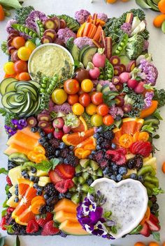 an arrangement of fruits and vegetables arranged in the shape of a heart