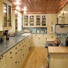 a large kitchen with wooden floors and white cupboards on the walls, along with wood flooring