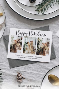 a holiday card on top of a table with silverware and pineconi branches