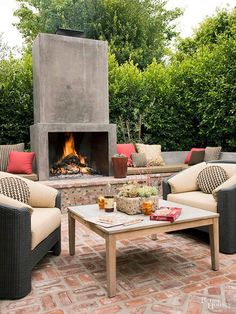 an outdoor living area with couches, tables and a fire place in the center