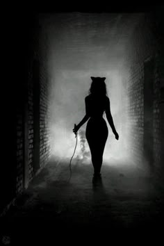 a woman walking down a dark alley way with a cat on her head in the fog