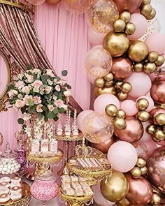 a table filled with lots of desserts and balloons in front of a pink wall