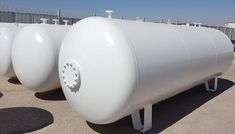 three large white tanks are lined up on the ground