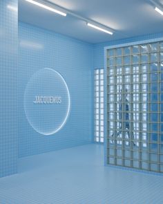 an empty room with blue tile walls and glass doors that read jalecquemus