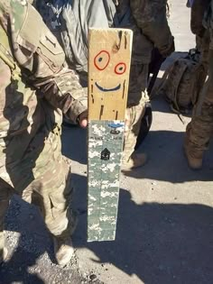 a person holding a skateboard with a smiley face on it's side and other soldiers in the background