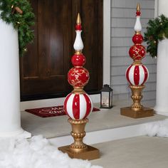 two red and white christmas balls sitting on top of each other in front of a door