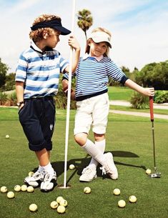 two young boys standing next to each other on top of a green golf ball field