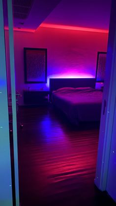 a bed sitting in a bedroom next to a purple and red light on the wall