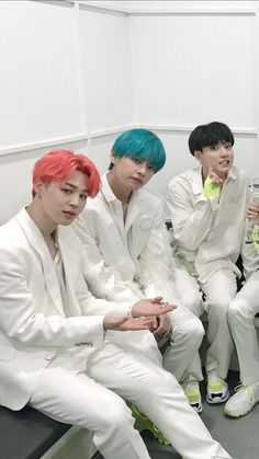 group of young men in white suits sitting next to each other and drinking drinks together