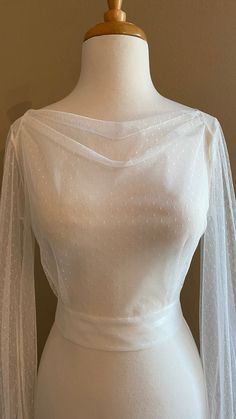 a mannequin wearing a white dress with sheer sleeves