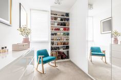 there is a closet with many pairs of shoes on the shelves and two blue chairs