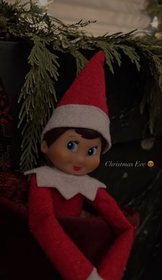 an elf is sitting in front of a christmas tree with her hands on her hips