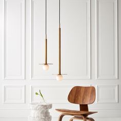 a wooden chair and vase with flowers in the middle on a white floor next to paneled wall