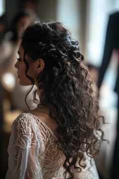 a woman with long curly hair wearing a white dress and looking off to the side