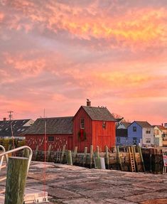 a red building sitting on top of a pier next to a body of water at sunset