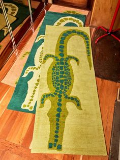 a green and blue rug with an image of a gecko on the floor in front of a mirror