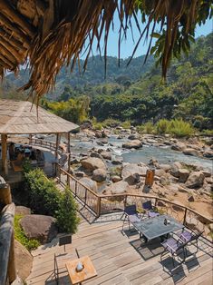 an outdoor dining area with chairs and tables next to a river in the jungles