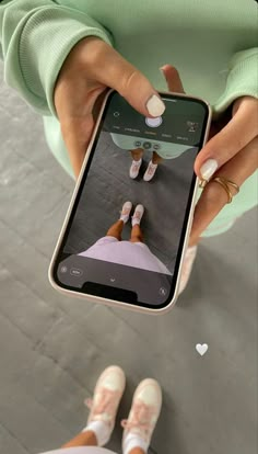 a woman is holding up her cell phone while she's wearing white slippers