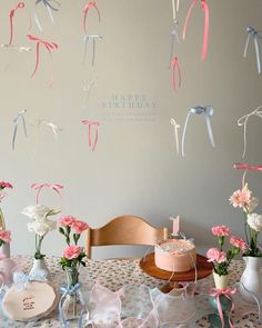 a table topped with vases filled with pink and white flowers next to a cake