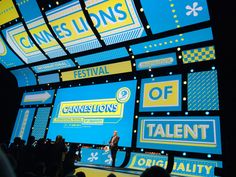 a man standing on top of a stage in front of a large screen with logos