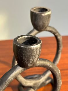 two metal candlesticks sitting on top of a wooden table