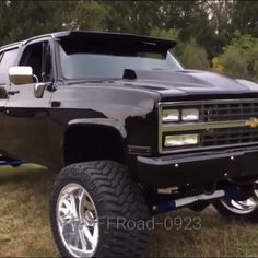 a black truck parked on top of a grass covered field