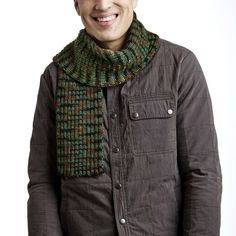 a smiling man wearing a green and brown knitted neckwarf with pockets on both sides