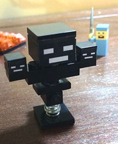 a small black object sitting on top of a wooden table next to a slice of pizza