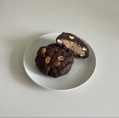 two chocolate cookies on a white plate with peanut butter