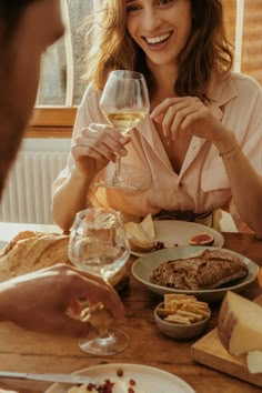 a woman sitting at a table holding a glass of wine