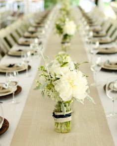 a long table is set with white flowers and place settings