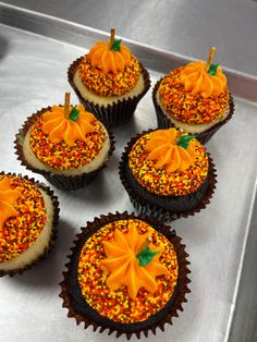 six cupcakes decorated with orange and yellow sprinkles