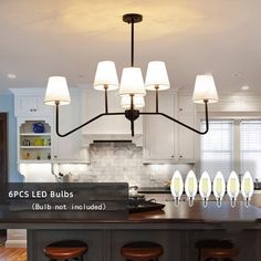 a kitchen island with six lights hanging from it's center and four stools in front of it