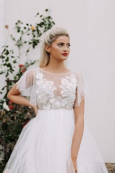 a woman wearing a white dress with sheer sleeves and flowers on the bouncy