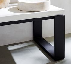 a white sink sitting on top of a counter next to a wooden bowl and vase