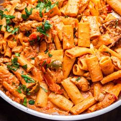 a bowl filled with pasta and meat covered in sauce, garnished with parsley