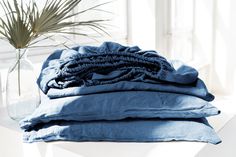 a stack of blue linens sitting on top of a table next to a plant