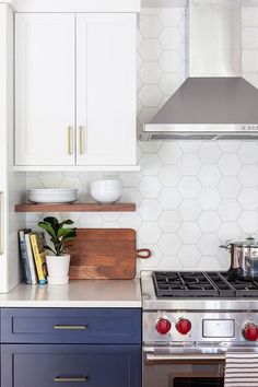 a stove top oven sitting inside of a kitchen next to white cupboards and drawers