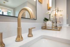 a bathroom sink with two gold faucets and a mirror in the back ground