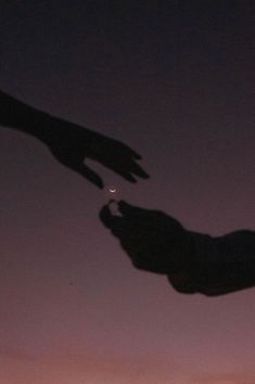 two people reaching out towards each other in the air at sunset or dawn with their hands outstretched