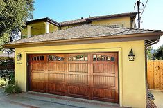 a yellow house with two brown garage doors