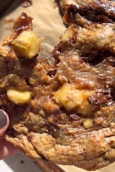 a person holding up a cookie with chocolate and bananas on it, in their left hand