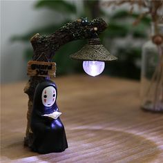 a small figurine sitting on top of a wooden table next to a lamp