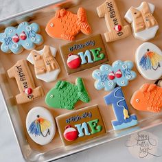 decorated cookies in the shape of numbers and fish are on a cookie sheet, ready to be eaten